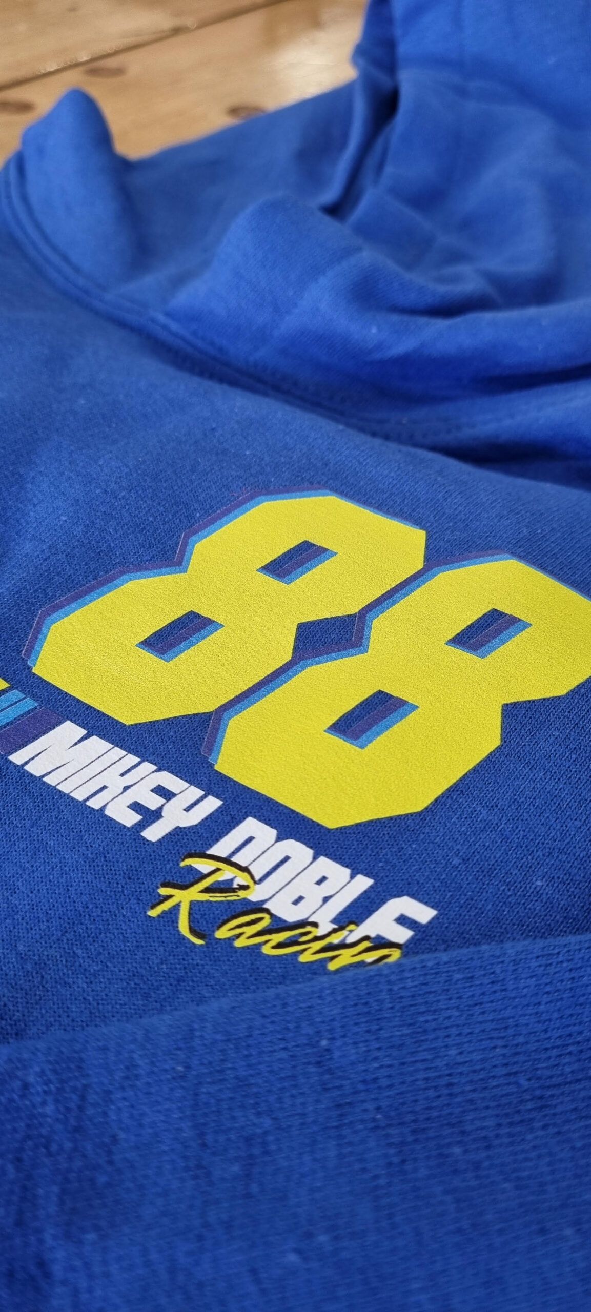 A blue #88ARMY hoodie is on a mannequin in front of a brick wall.