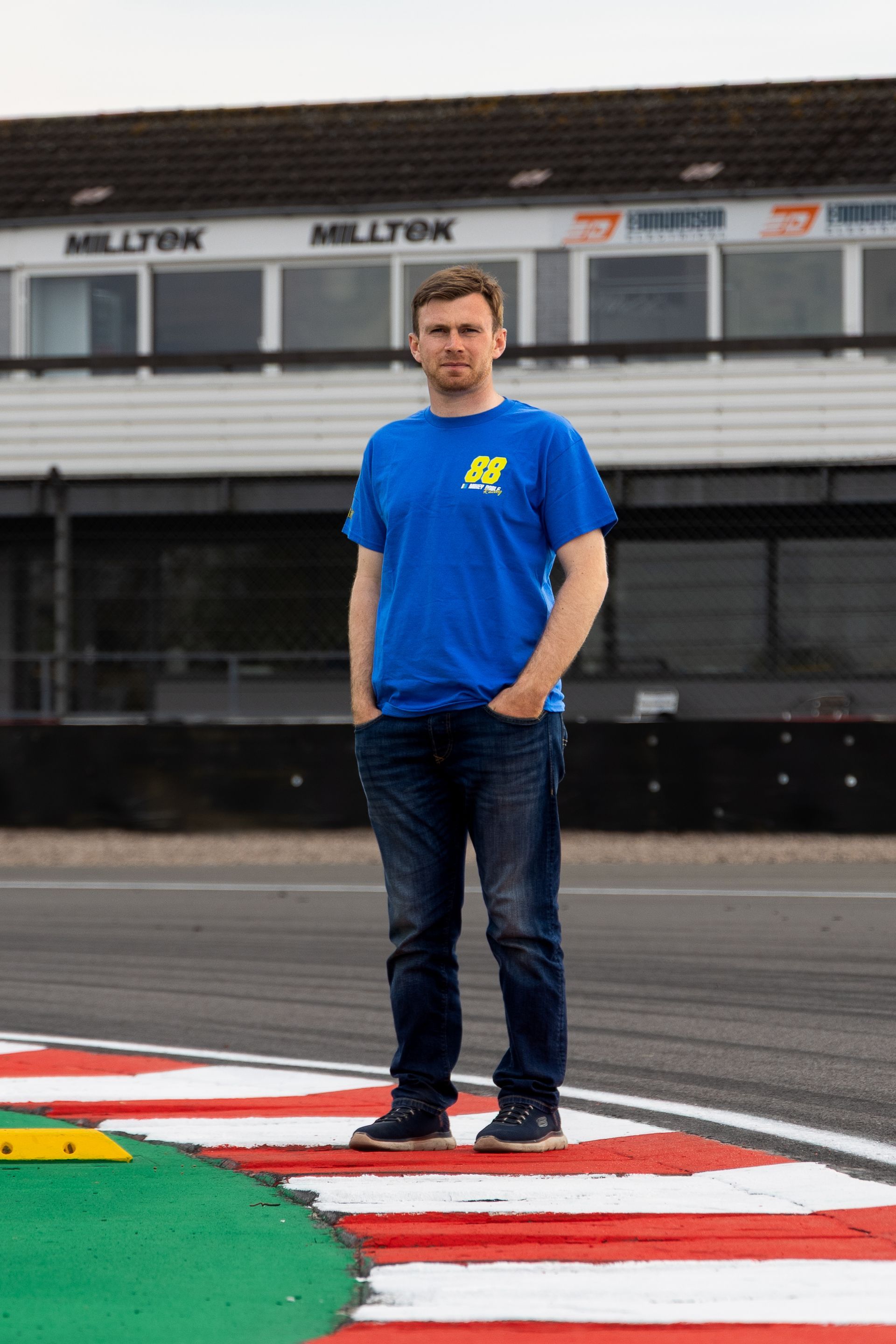 A man in a blue shirt is standing on a race track.