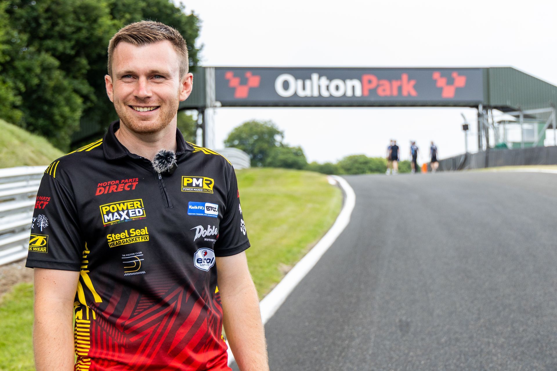 Mikey Doble on BTCC track walk smiling with Oulton Park bridge behind him