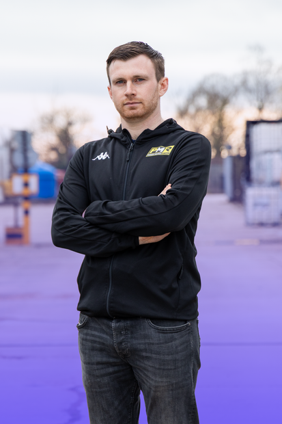 Mikey Doble standing with arms crossed and looking at camera