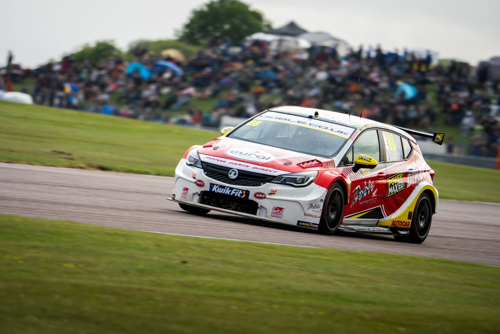 Mikey Doble on track at Thruxton 2025 BTCC with crowd in background cheering