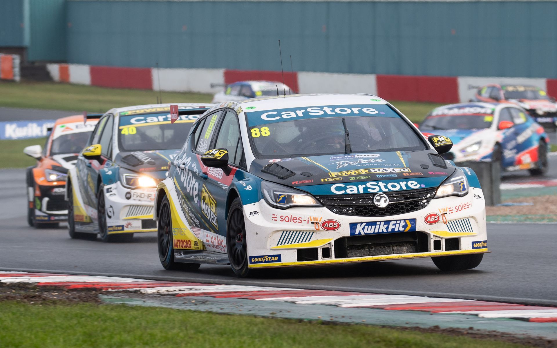 A group of racing cars are driving down a race track.