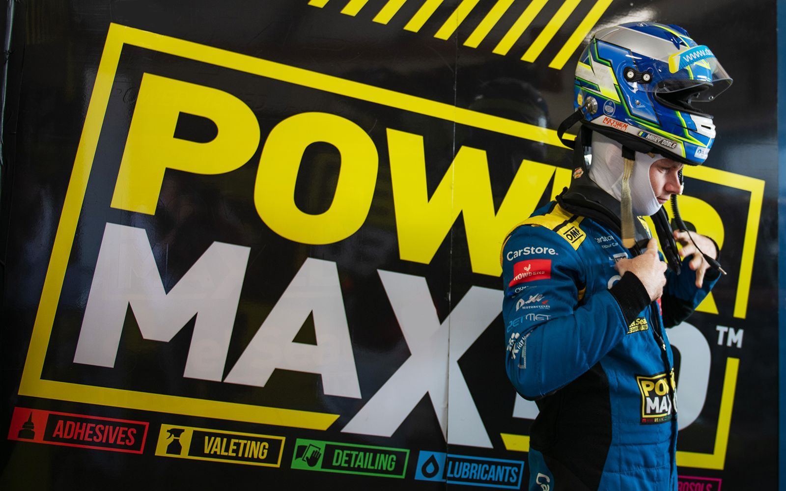 A man wearing a helmet stands in front of a power maxed sign
