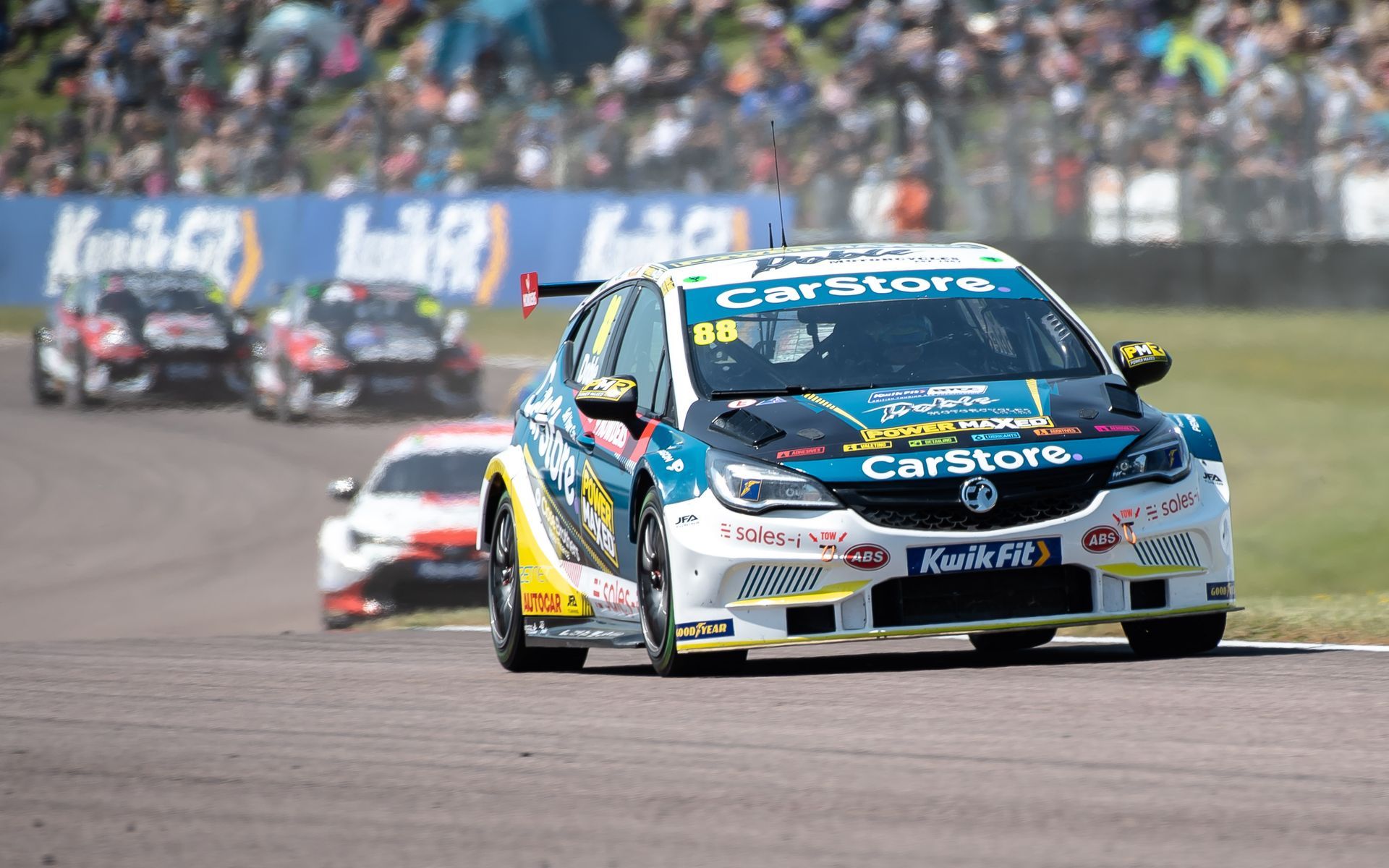A race car is driving down a race track in front of a crowd.