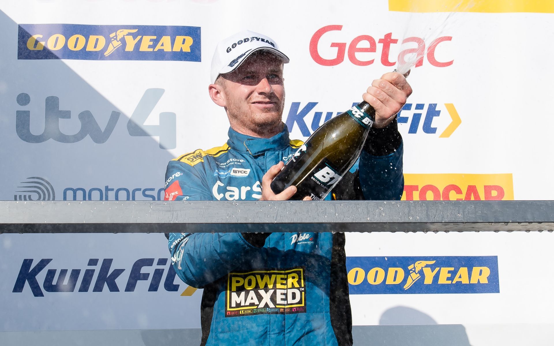 A man is standing on a podium holding a bottle of champagne.