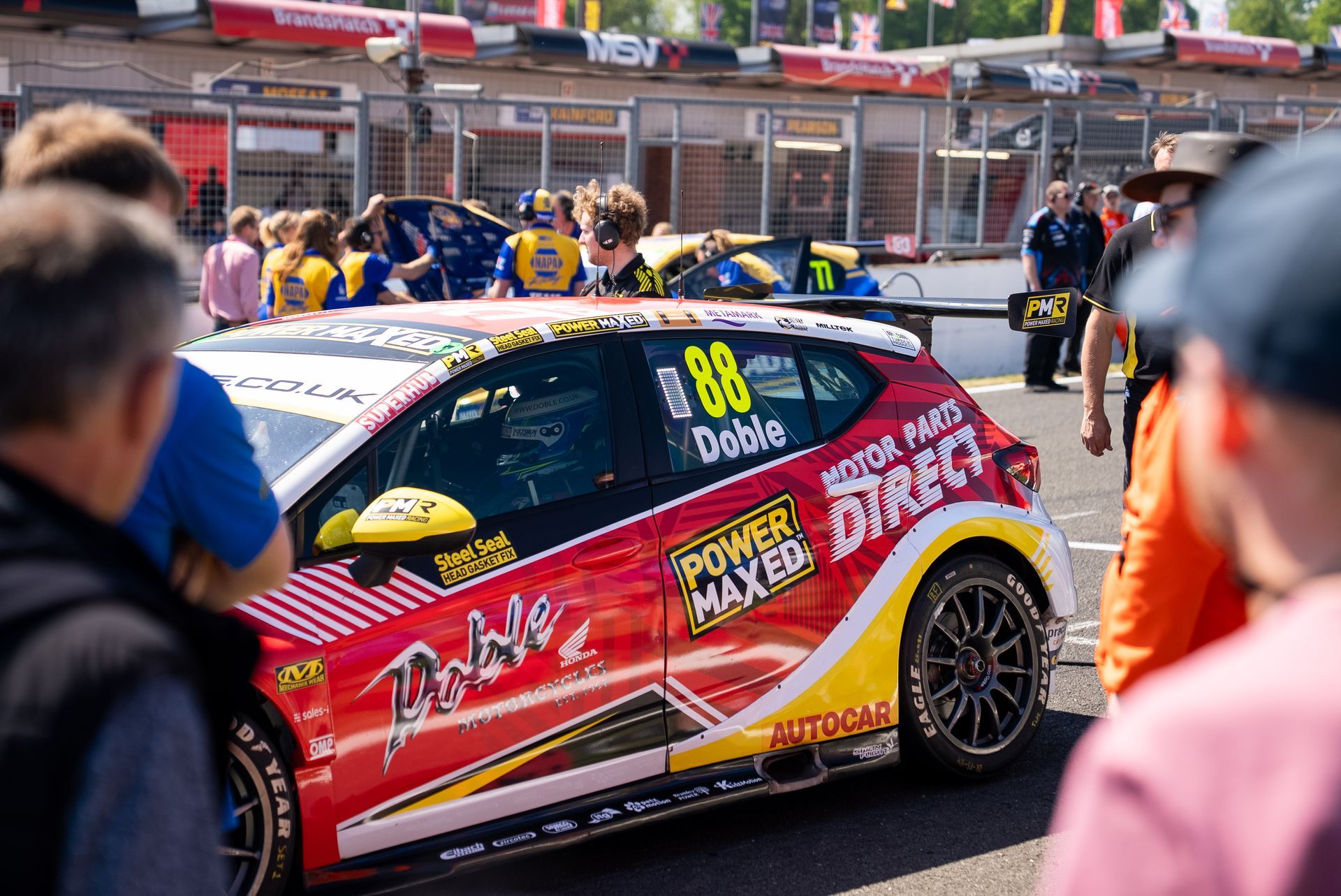 A group of people are standing around a race car on a track.