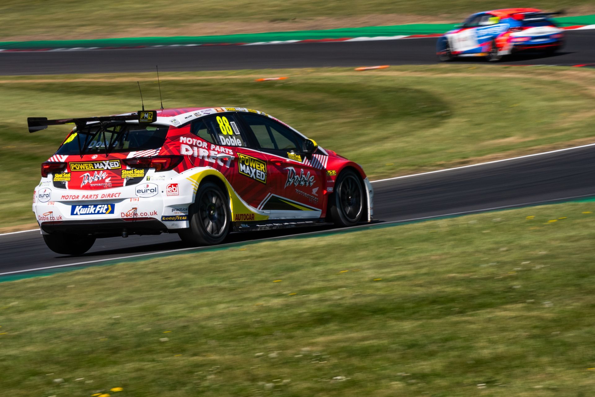 A red and white race car is driving down a race track.