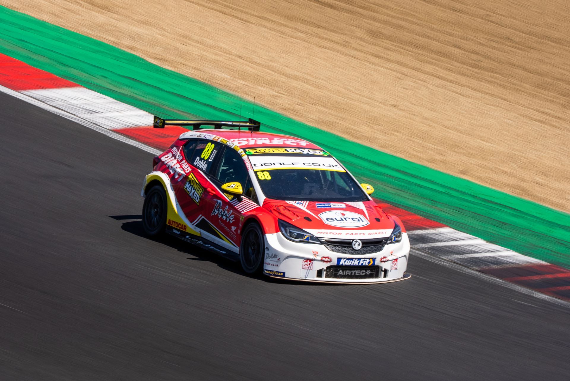 A red and white race car is driving down a race track.