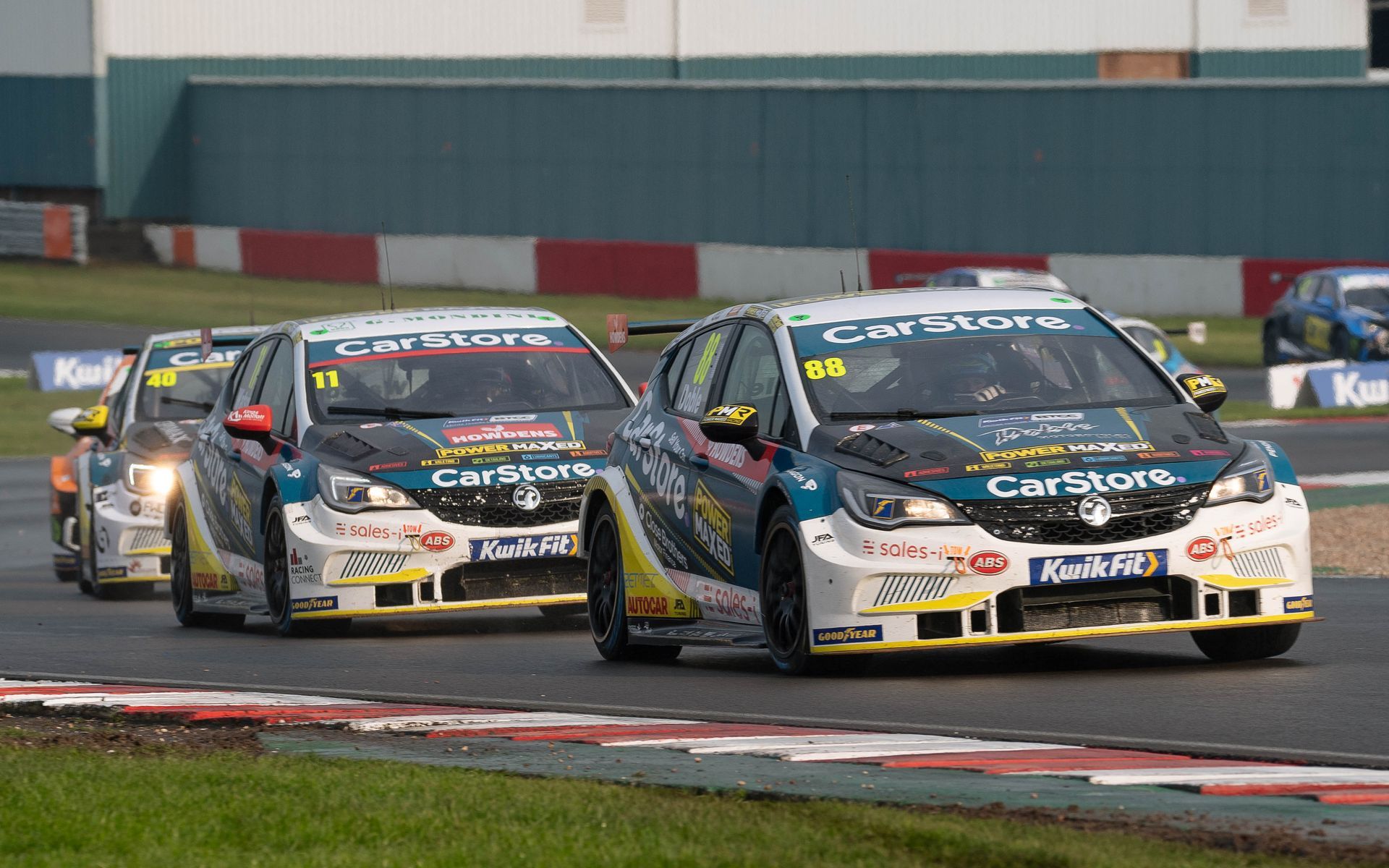A group of racing cars are driving down a race track.