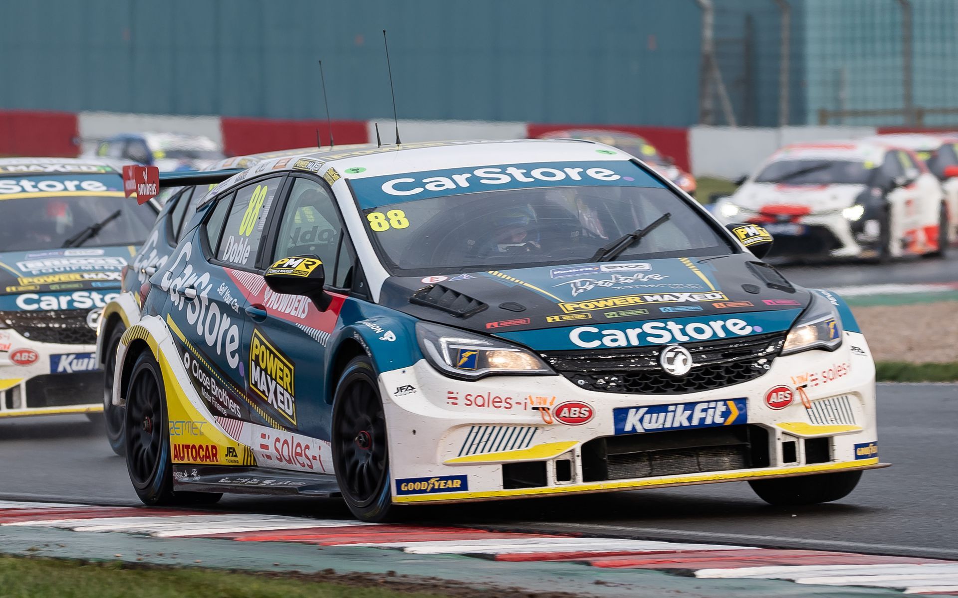 A group of racing cars are driving down a race track.
