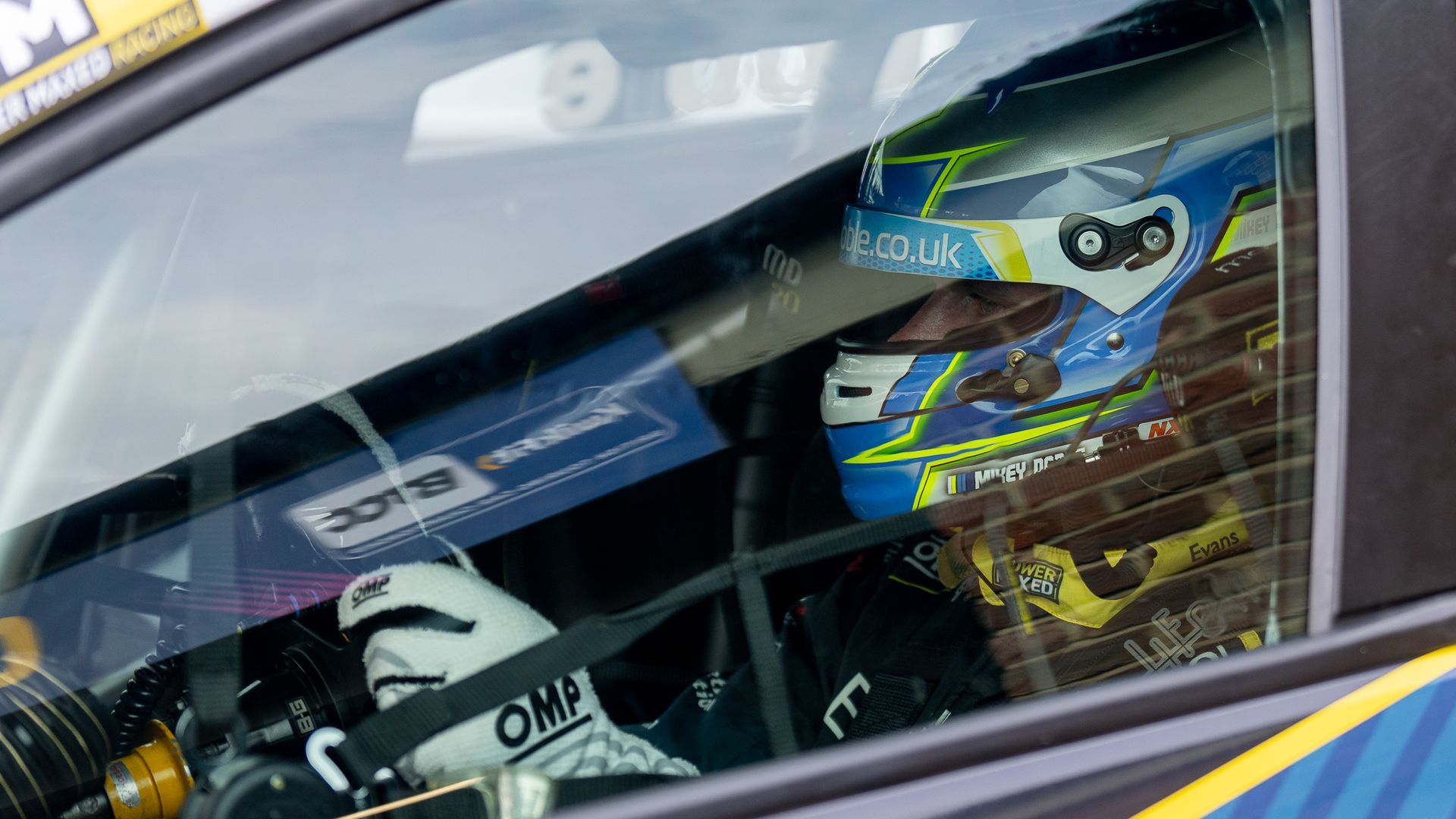 A man is sitting in the driver 's seat of a race car.