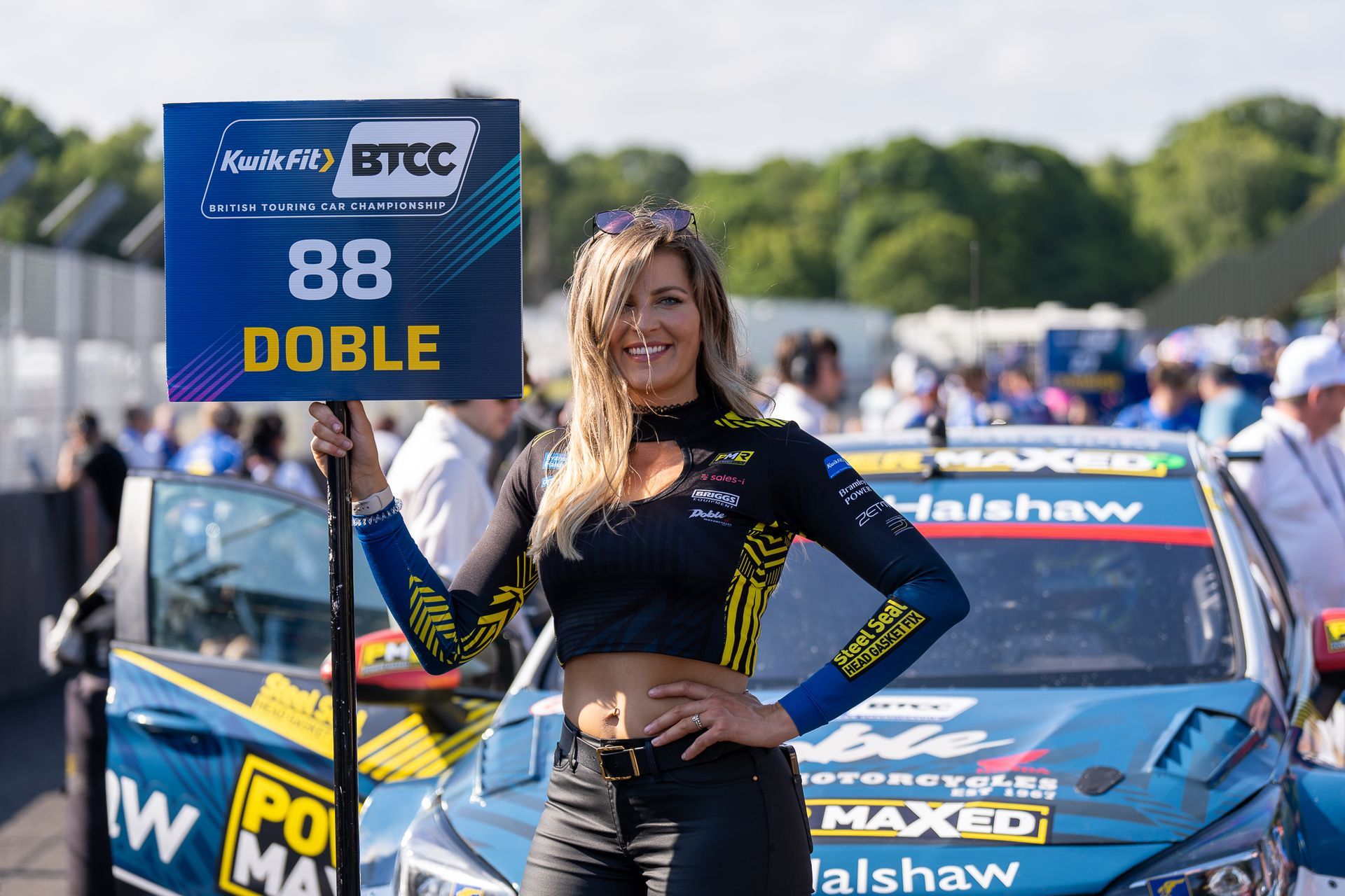A woman is holding a sign in front of a race car.