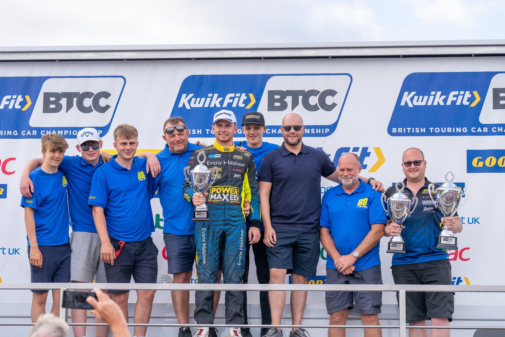 A group of men are posing for a picture in front of a btcc sign.