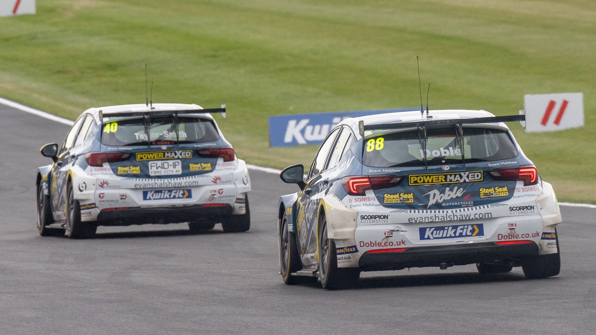 Two race cars on a track with a sign that says kuwait