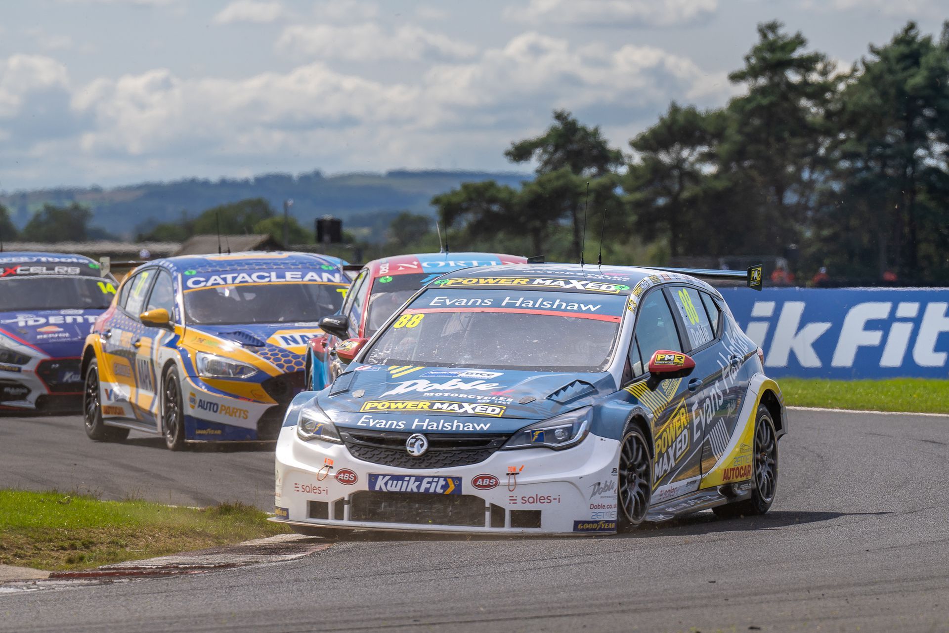 A group of race cars are racing on a track.
