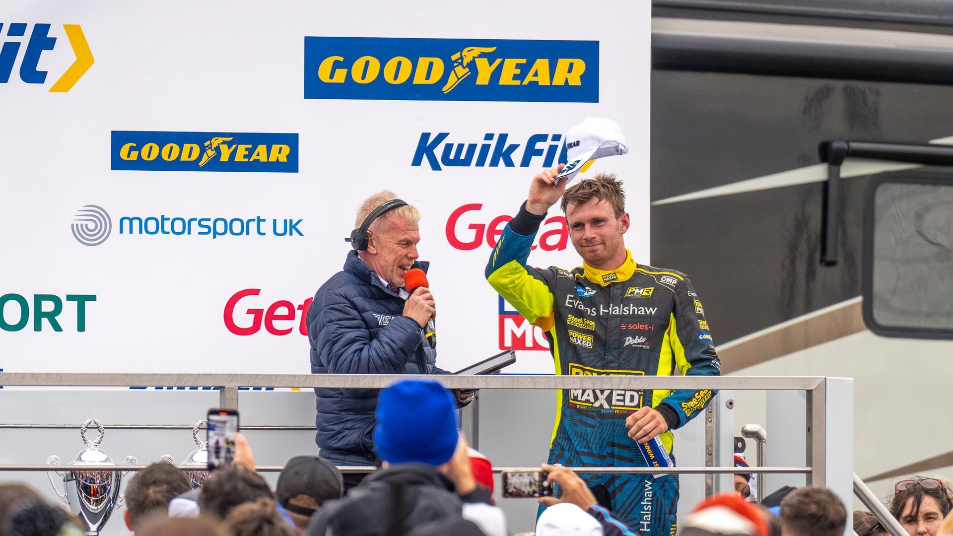 A man is holding a trophy in front of a crowd of people.