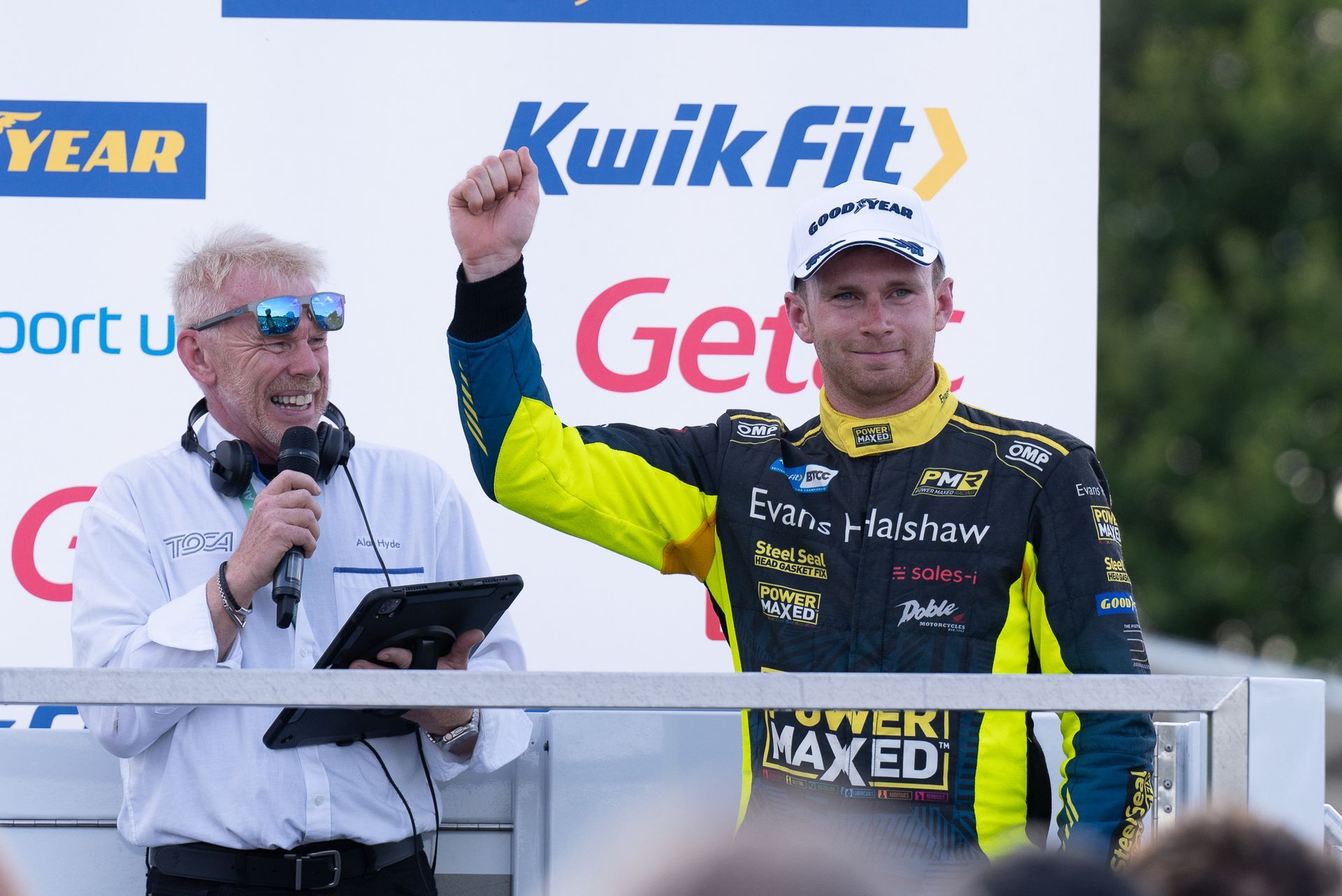 Two men are standing in front of a sign that says kwik fit