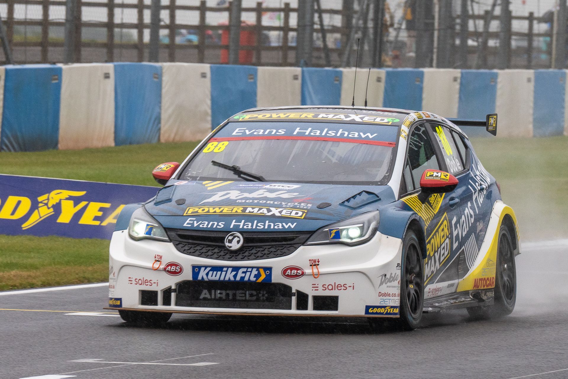 A race car is driving on a track with a sign that says hawk fit