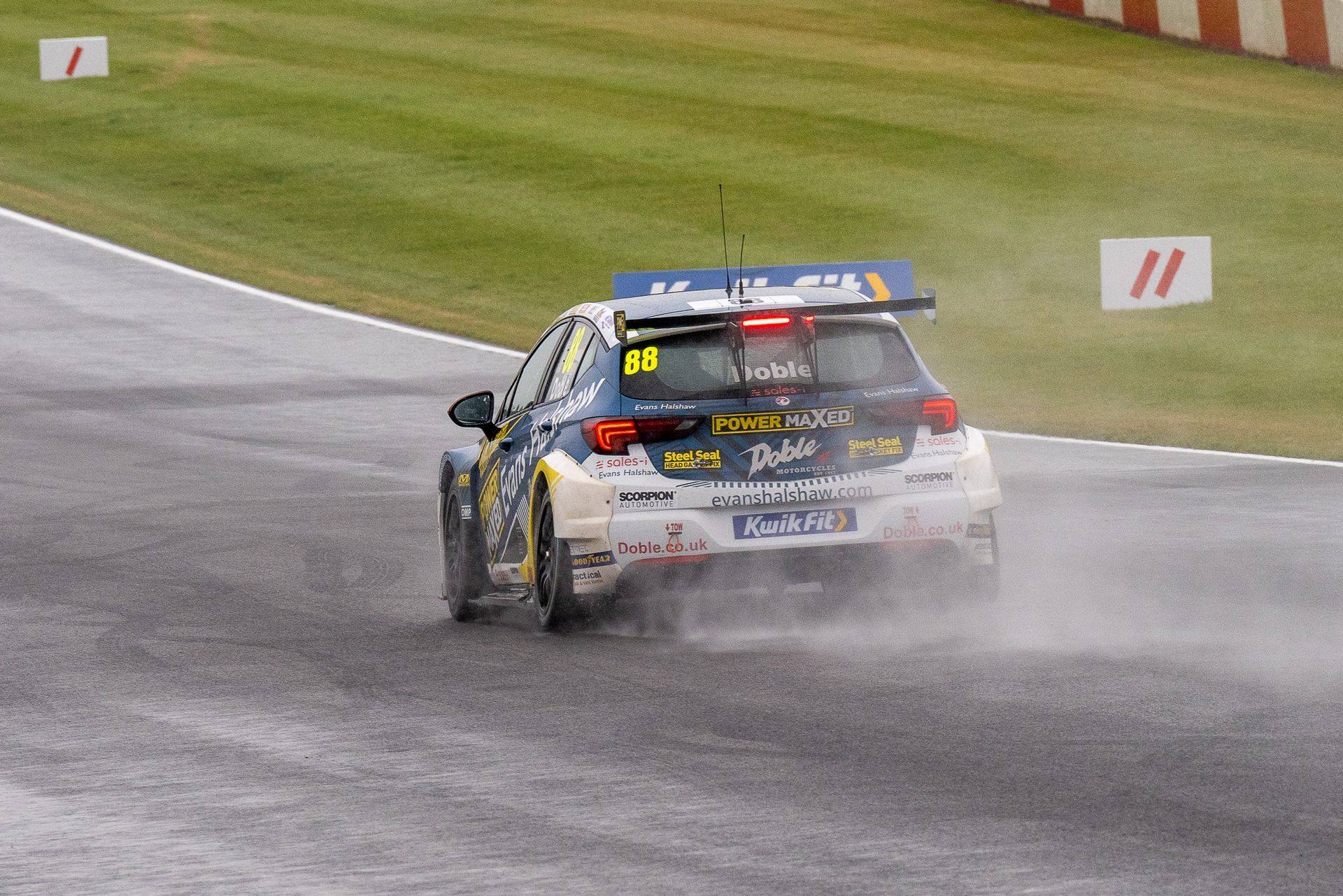 A race car is driving on a wet track.