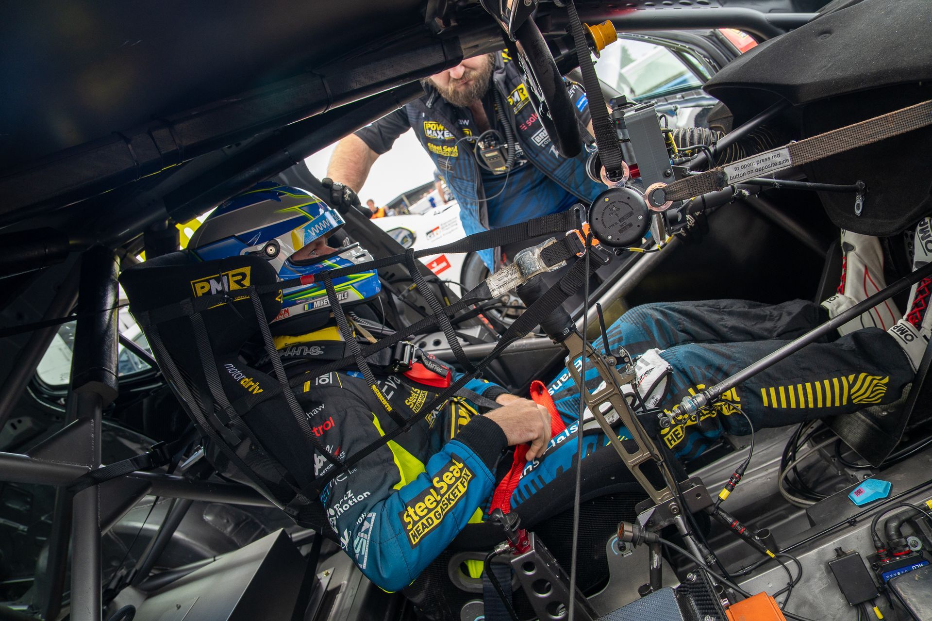 A man is working on the inside of a race car.
