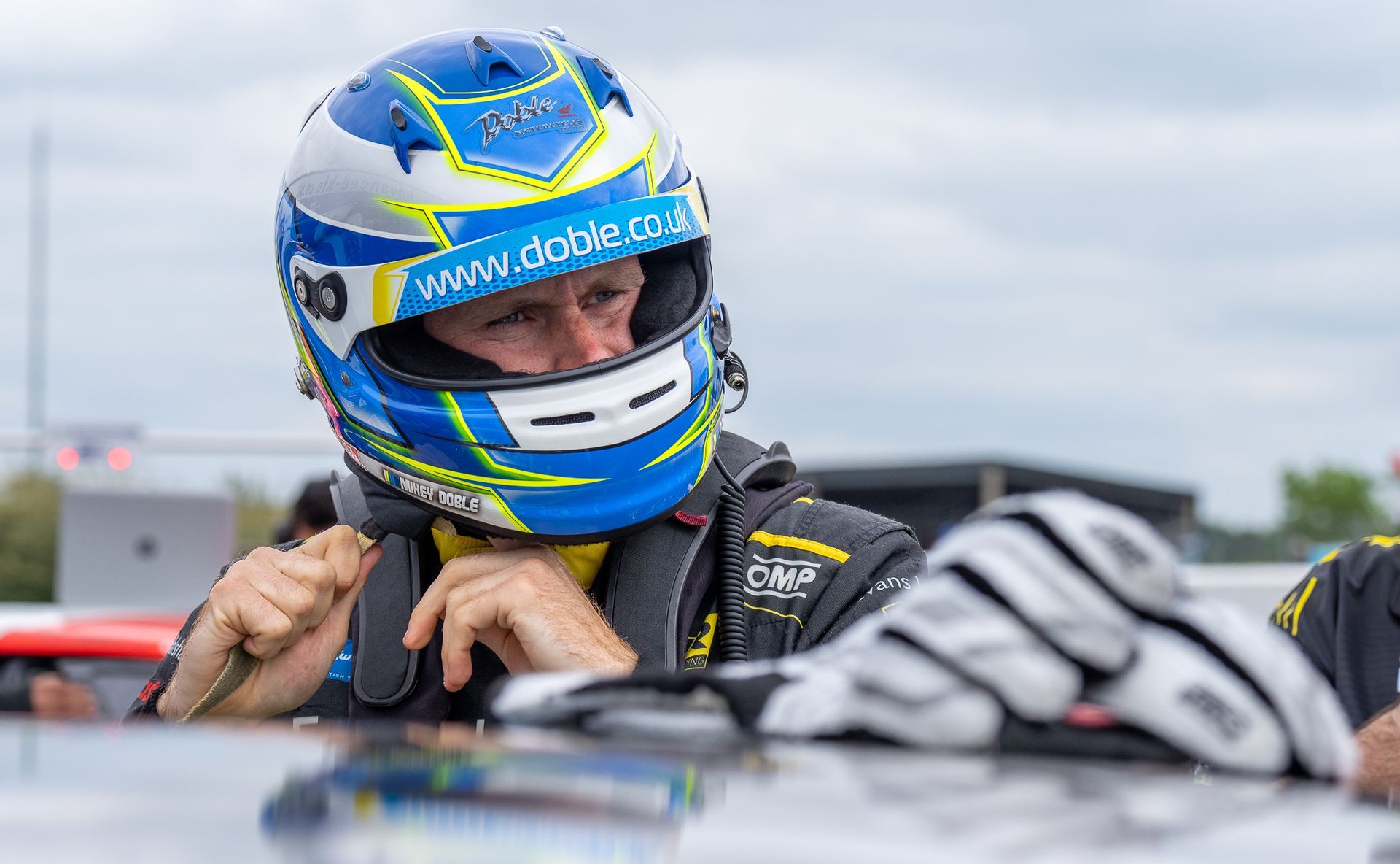 A man wearing a helmet and gloves is sitting in a car.