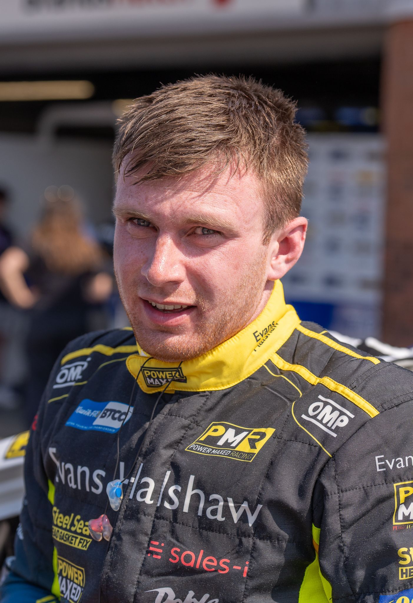 A man is wearing a black and yellow racing suit.