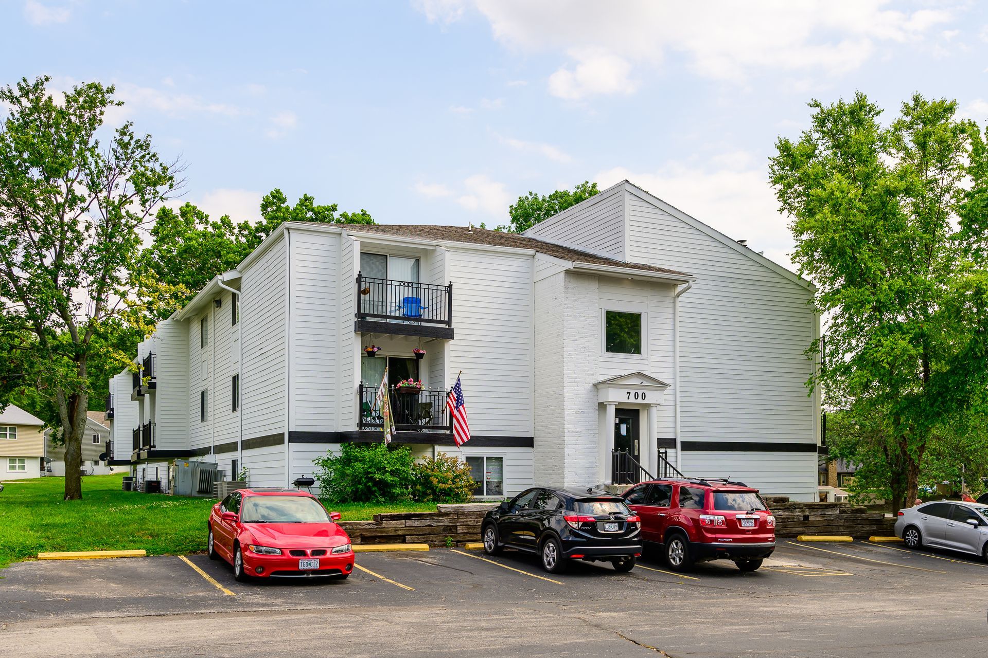 A white apartment building with cars parked in front of it