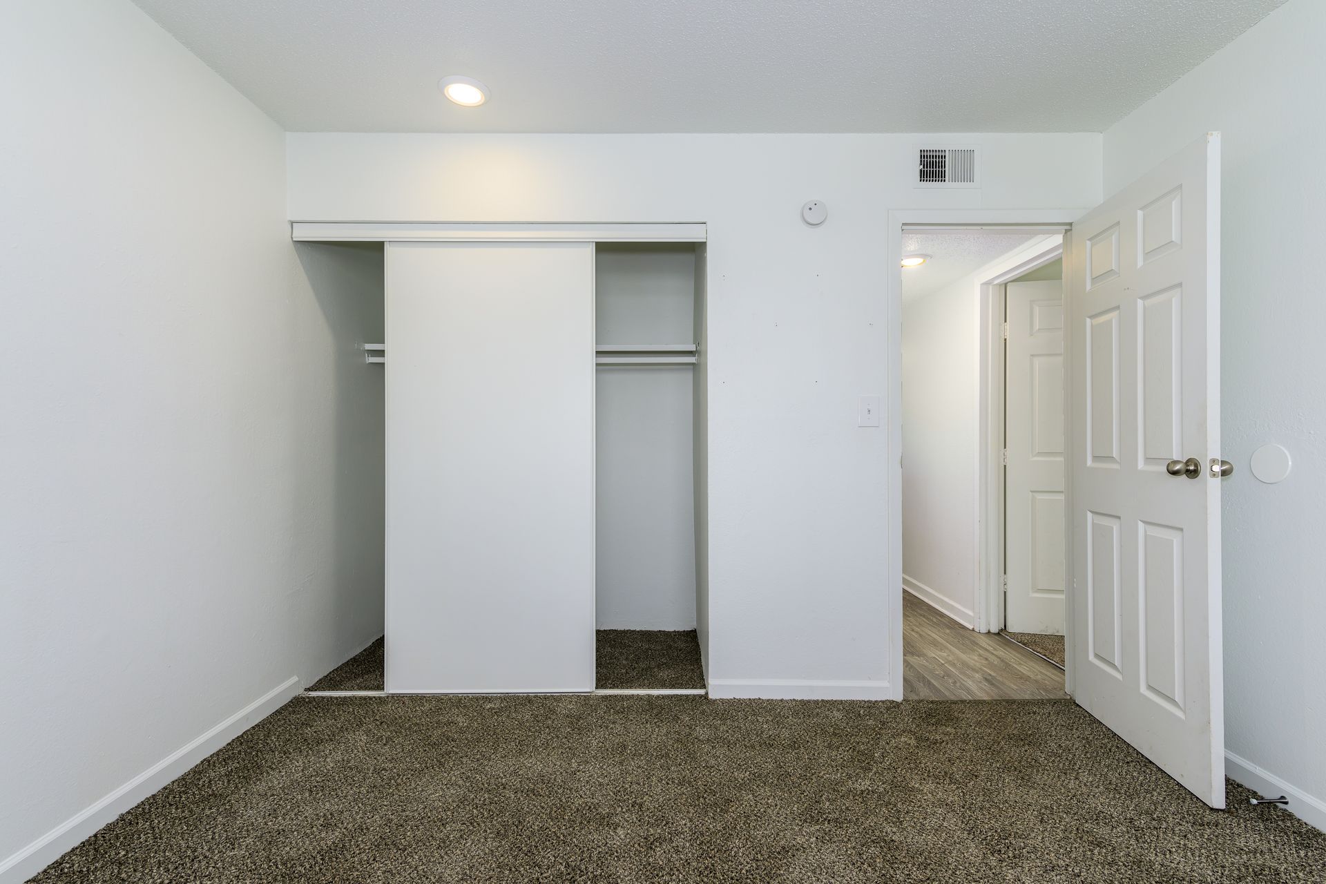 An empty bedroom with sliding glass doors and a closet.