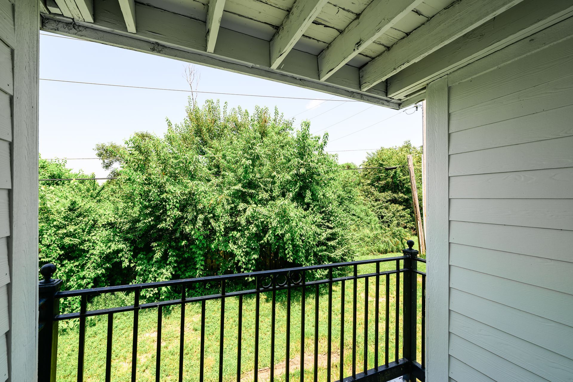 A balcony with a black railing and trees in the background