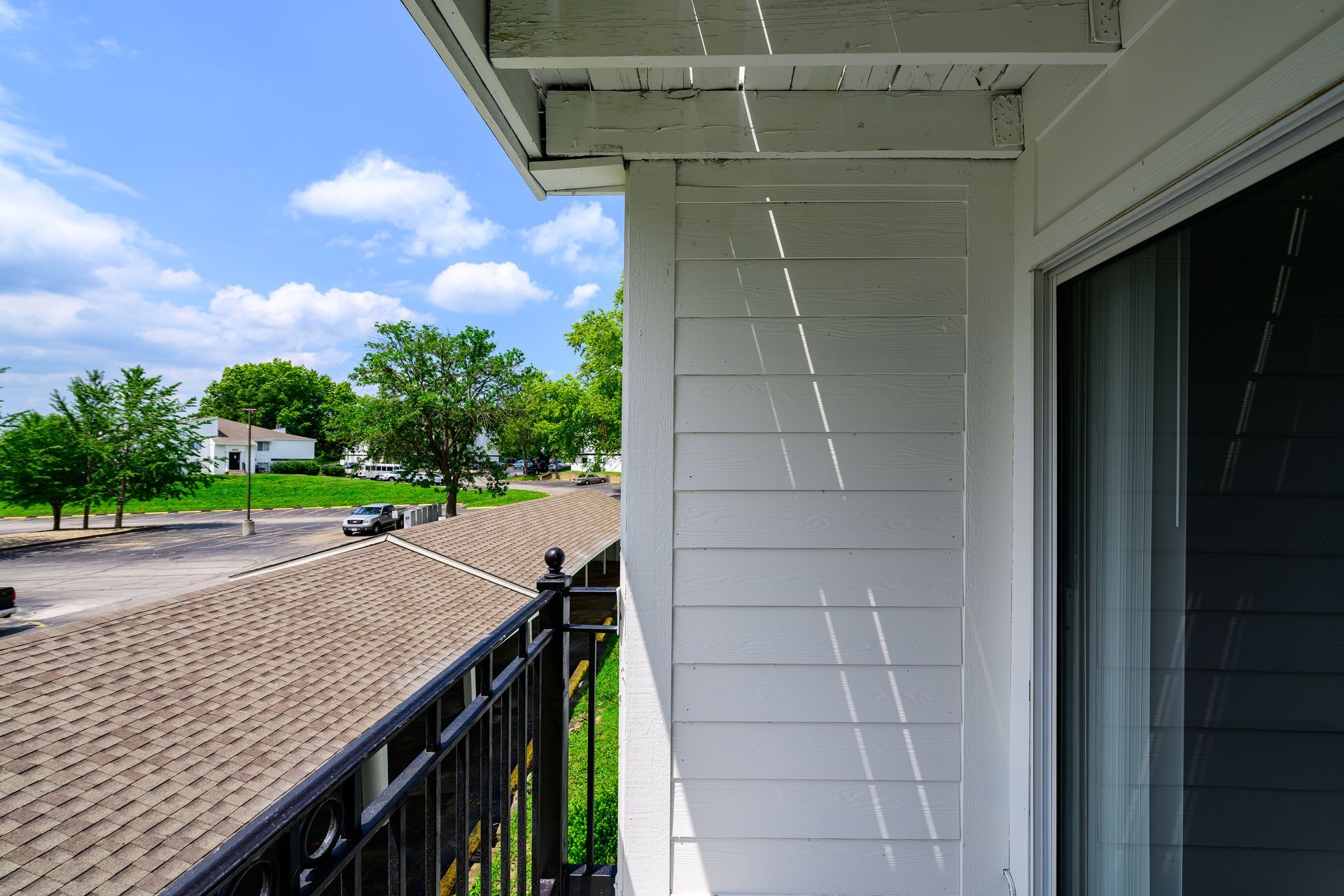 A balcony with a view of a roof and trees.