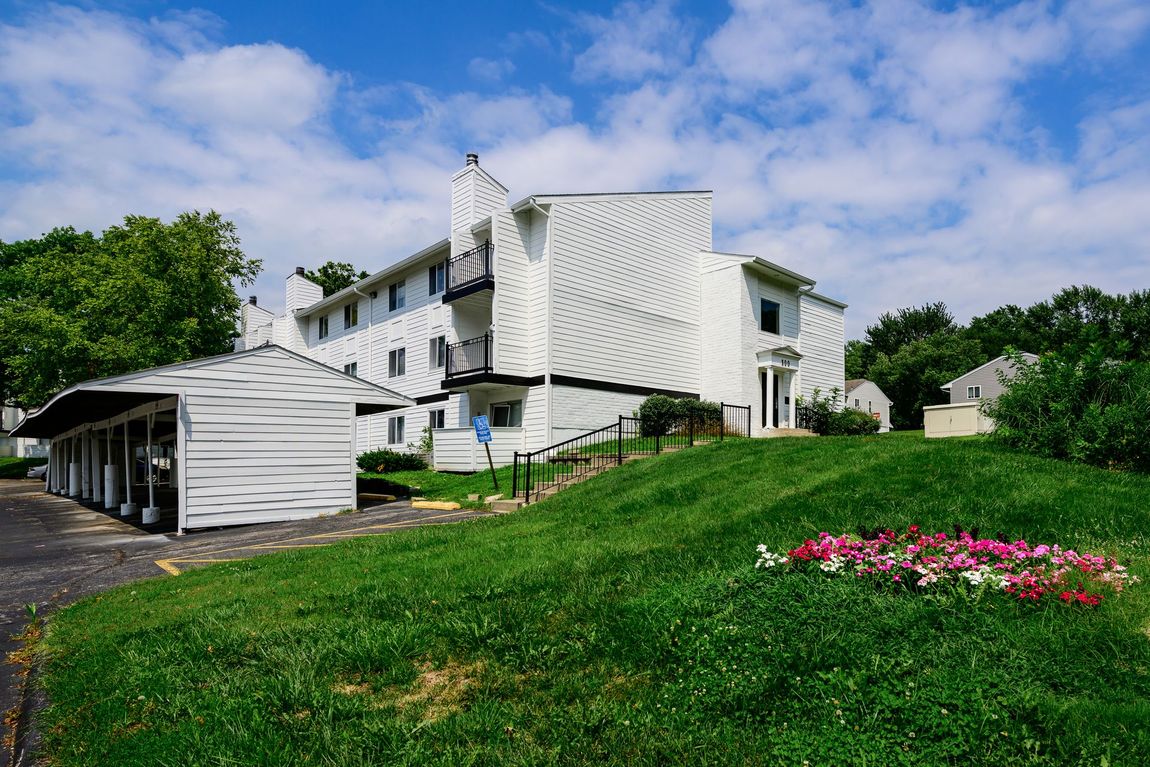 A large white building is sitting on top of a lush green hill.