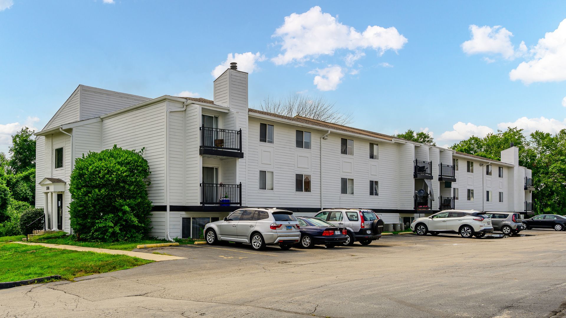 A large white apartment building with cars parked in front of it.