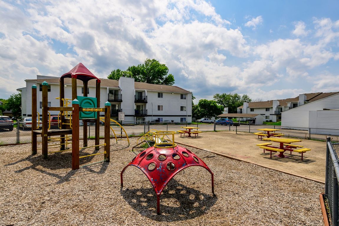 A playground with a red climbing structure in front of a building.