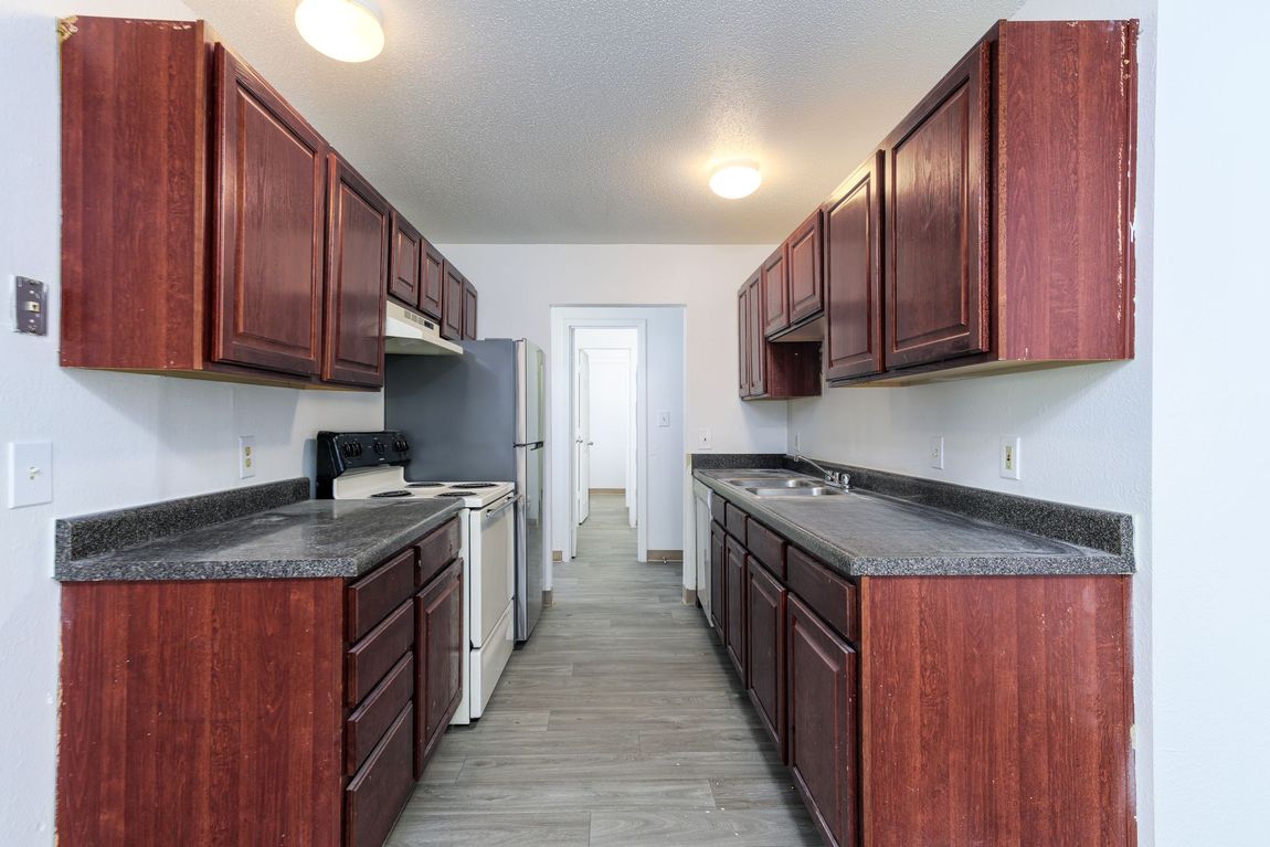 A kitchen with wooden cabinets and granite counter tops.