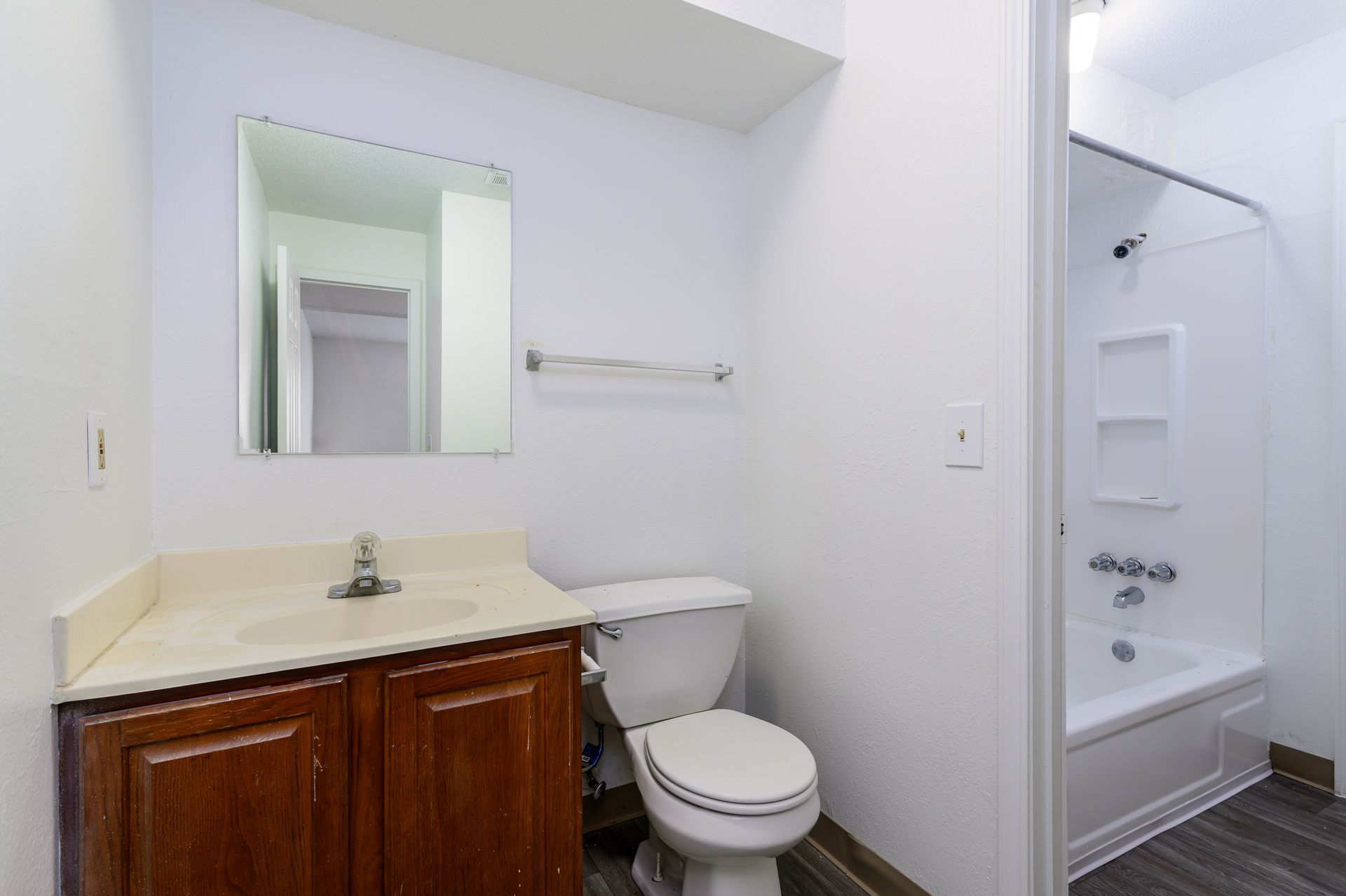 A bathroom with a toilet , sink , mirror and bathtub.