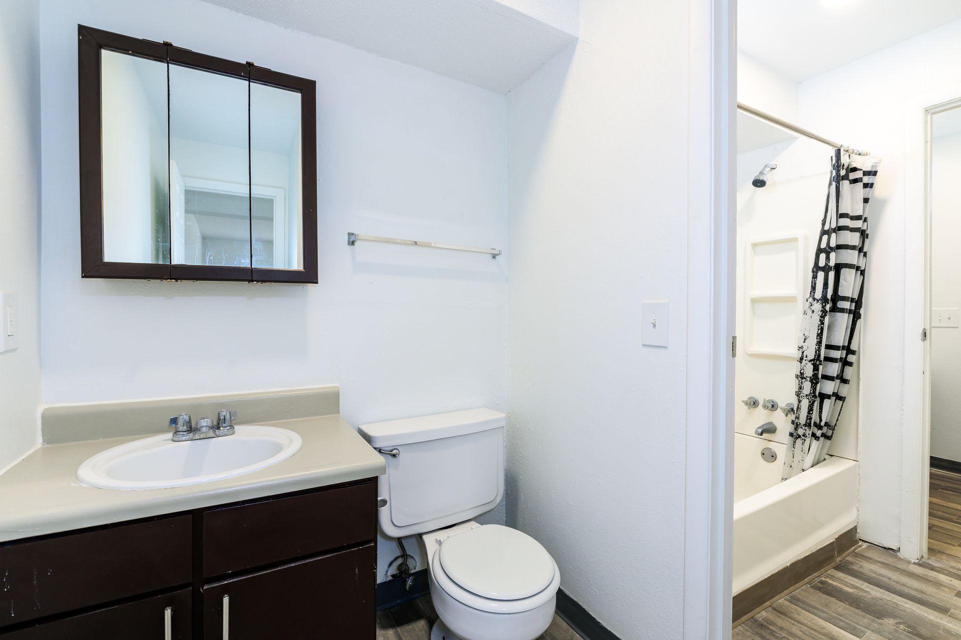A bathroom with a toilet , sink , mirror and shower.