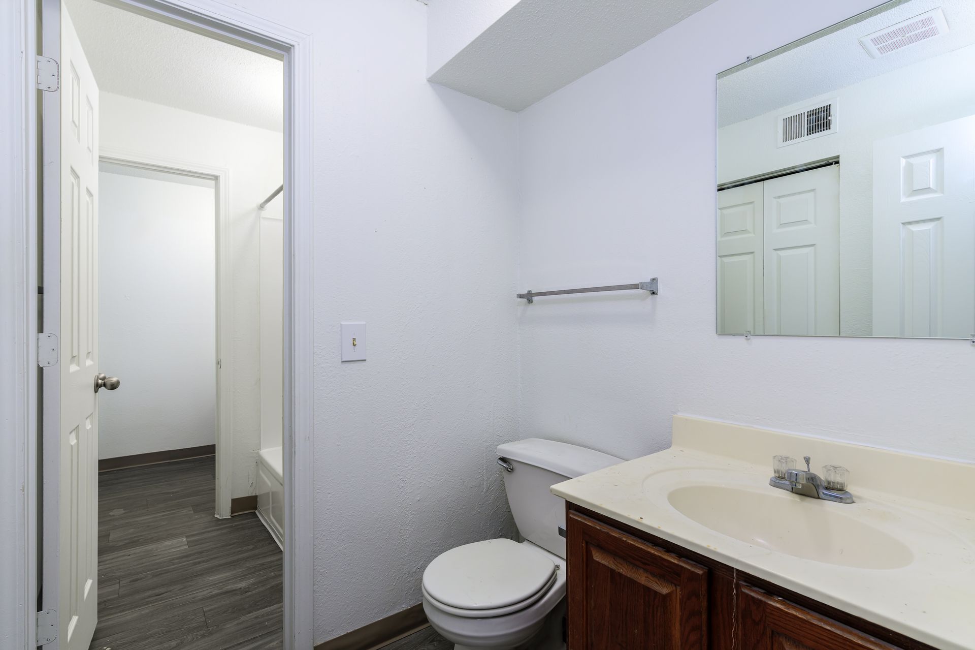 A bathroom with a toilet , sink and mirror.