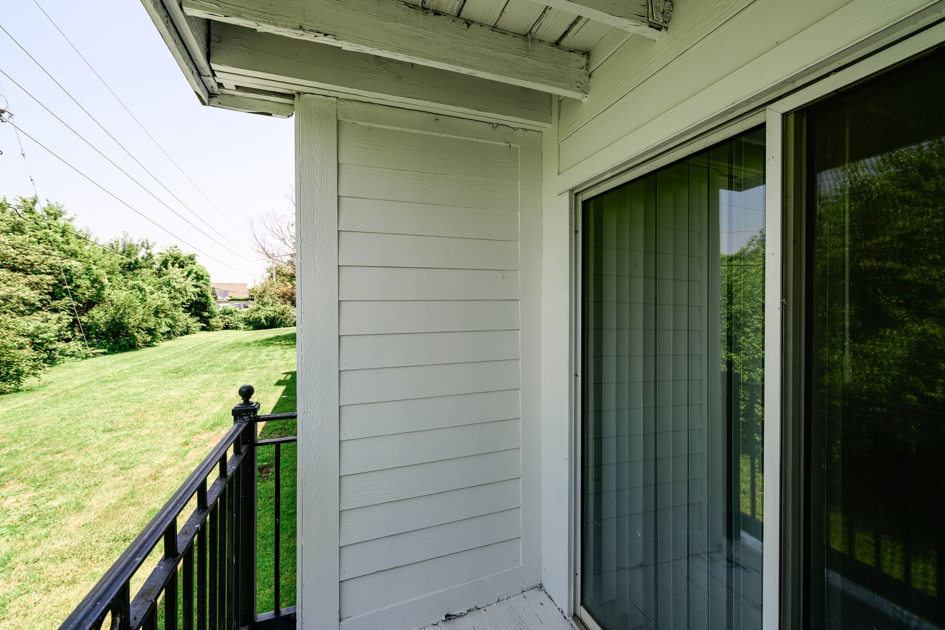 A balcony with a sliding glass door and a black railing.