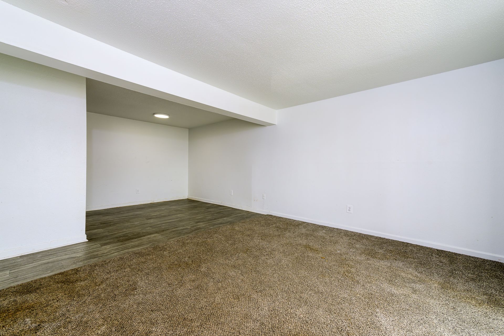 An empty room with a carpeted floor and white walls.