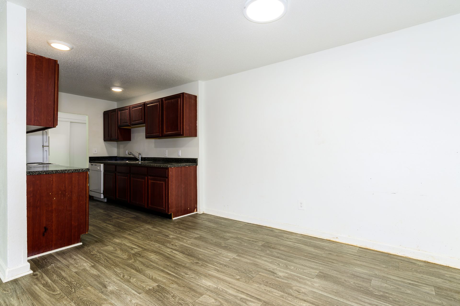 An empty kitchen with wooden cabinets and a wooden floor.