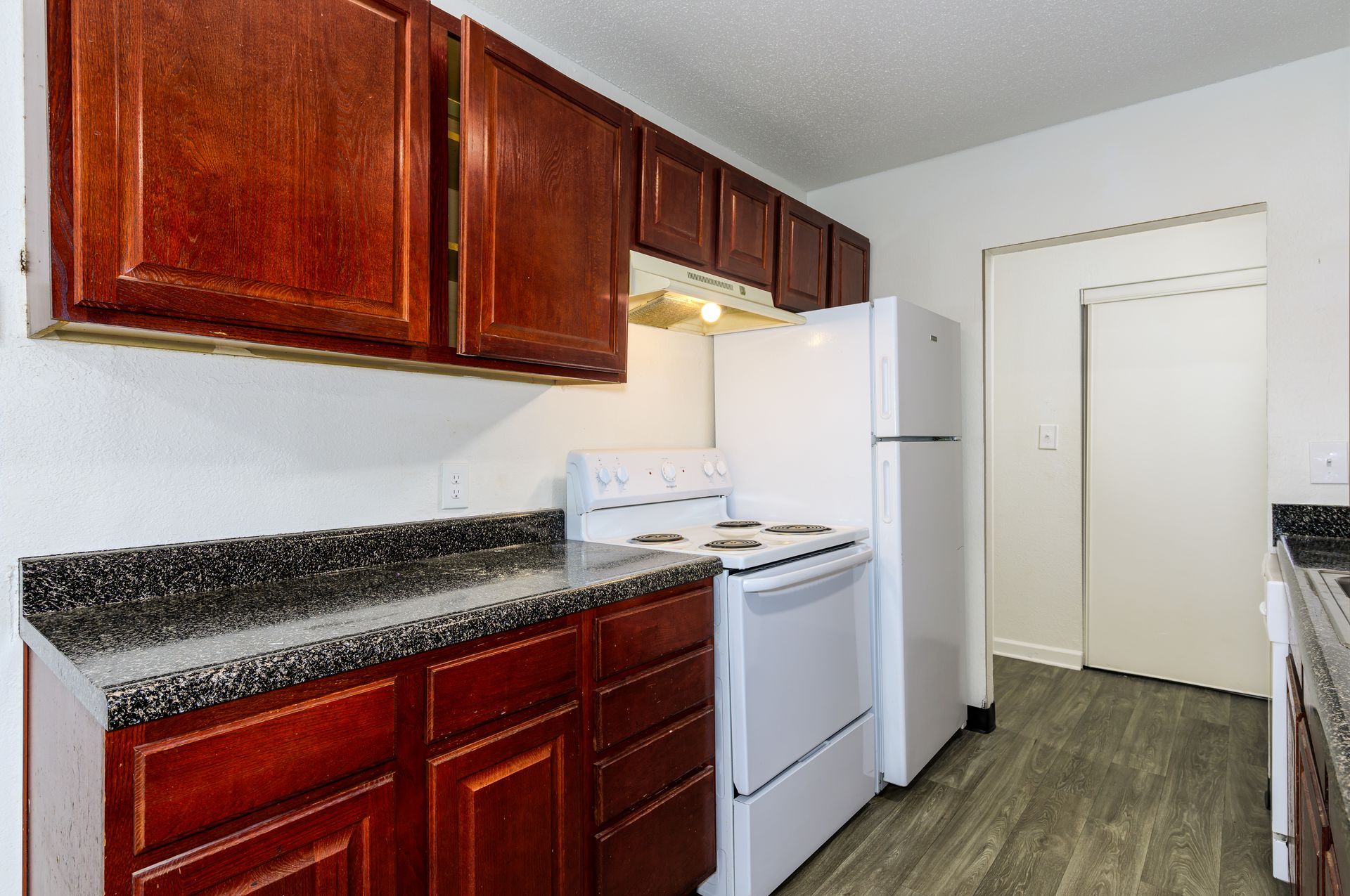 A kitchen with wooden cabinets , a white refrigerator , a stove , and a sink.