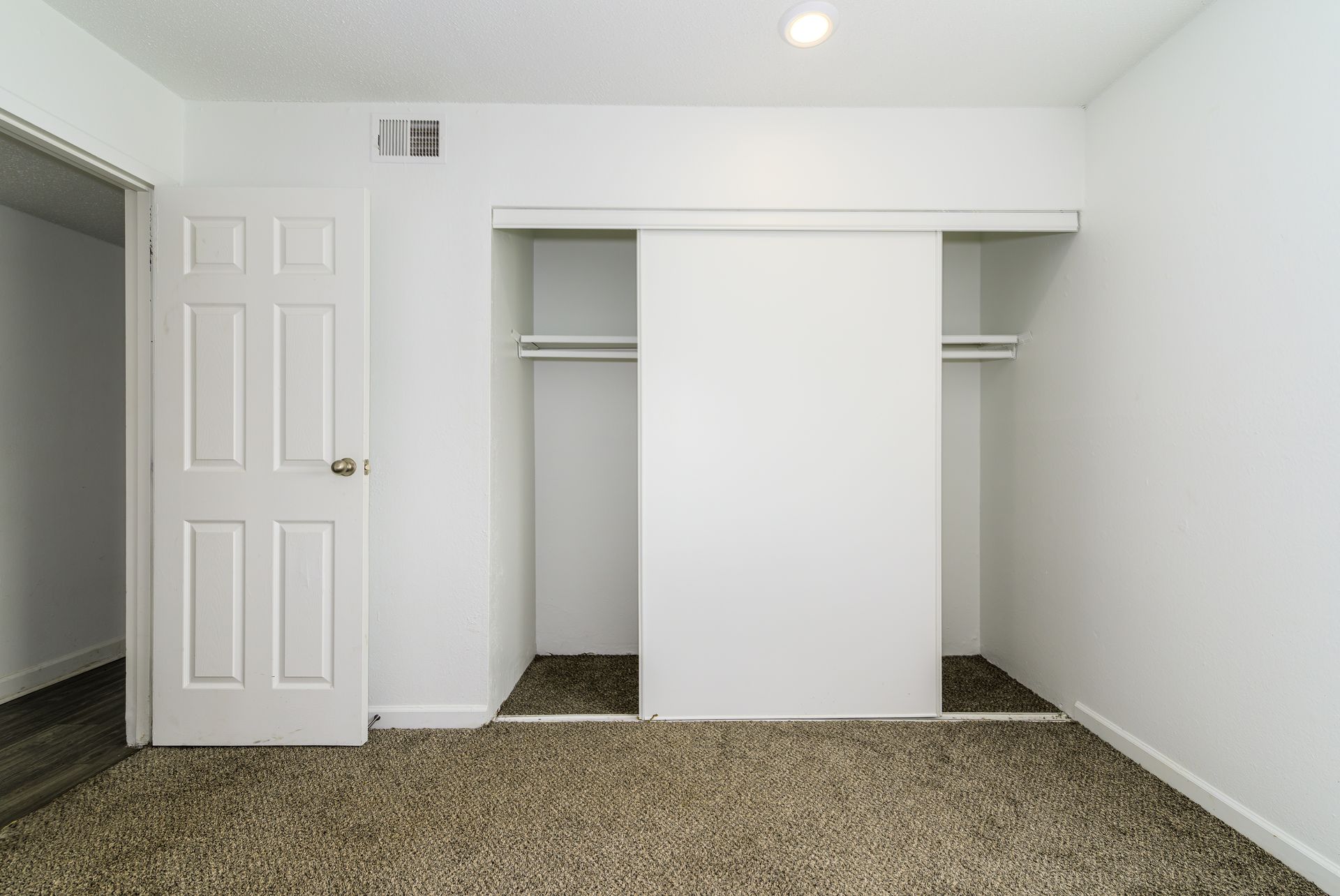 An empty bedroom with two closets and a door.