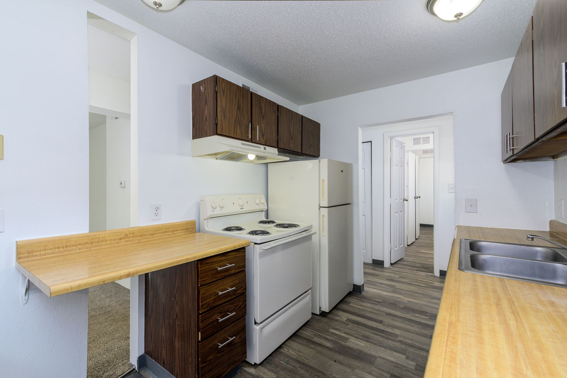 A kitchen with a stove , refrigerator , sink and wooden cabinets.