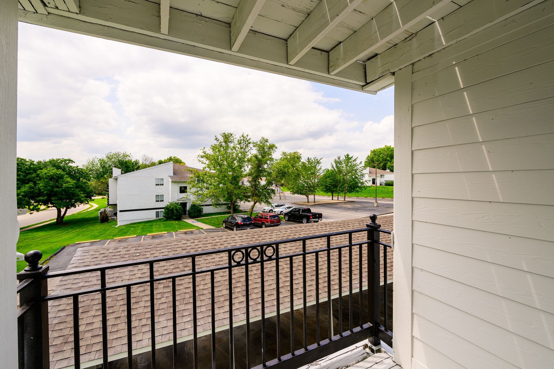 A balcony with a view of a parking lot and a house.