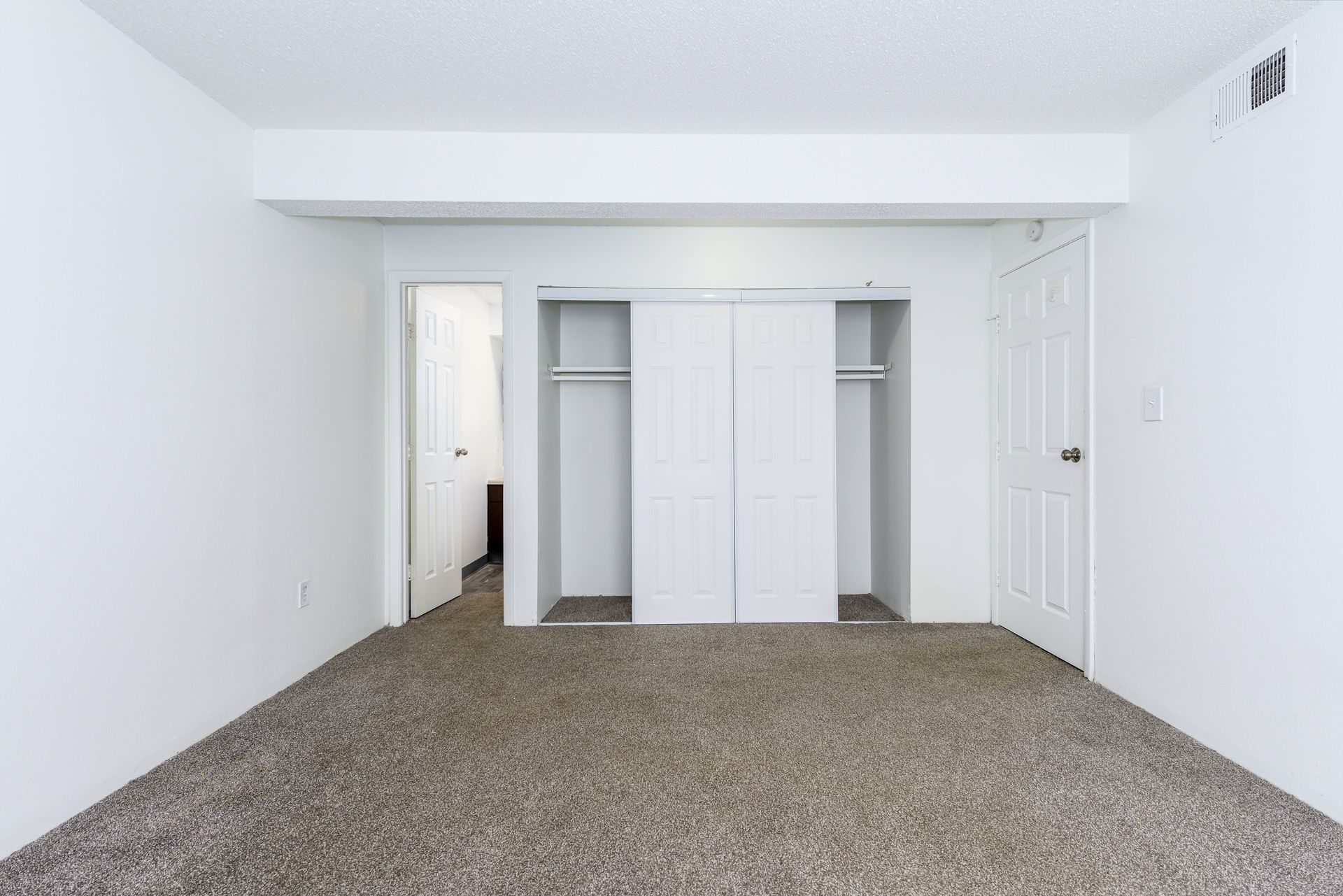 An empty bedroom with a carpeted floor and white walls.