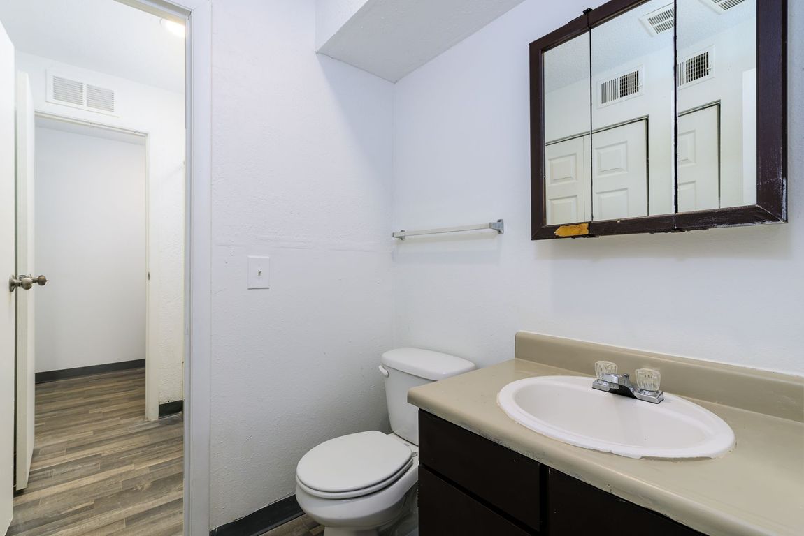 A bathroom with a toilet , sink and mirror.