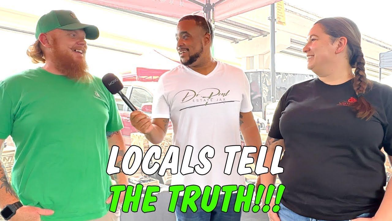 Three people outdoors, being interviewed. A man with a microphone interviews a man with a beard and a woman.