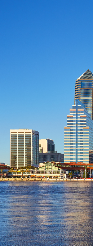 Modern living room with a kitchen, large windows, and various seating areas.