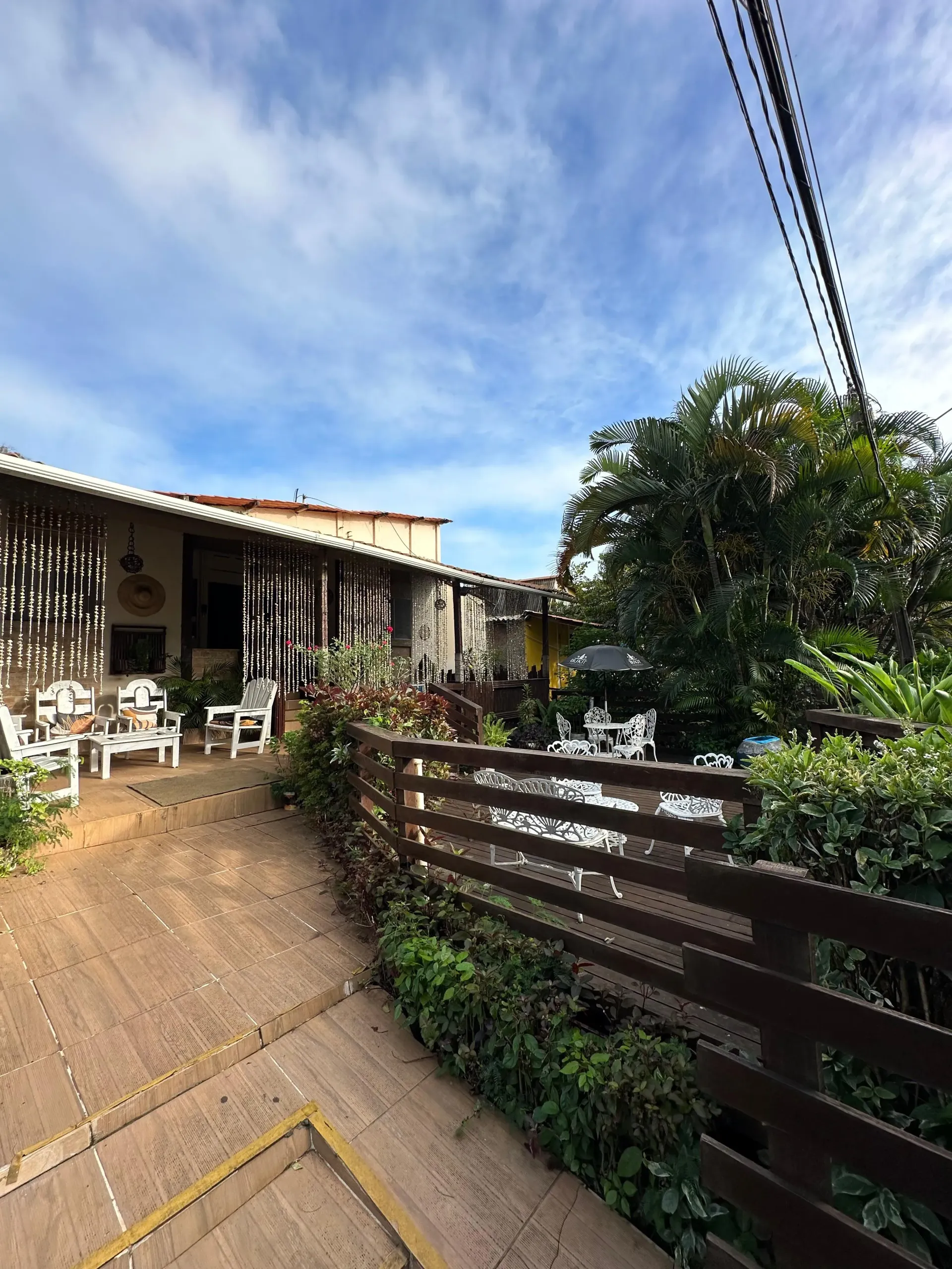 Um pátio com uma cerca de madeira e cadeiras em frente a uma casa. Pousada Golfinho Fernando de Noronha