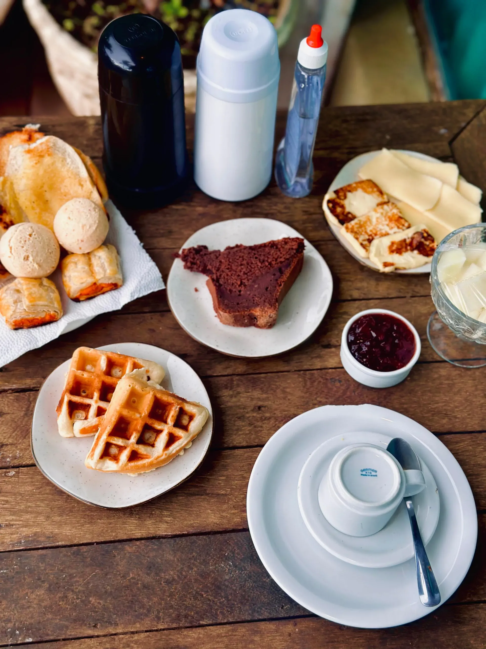Uma mesa de madeira coberta com pratos de comida e uma xícara de café. Pousada Golfinho Fernando de Noronha
